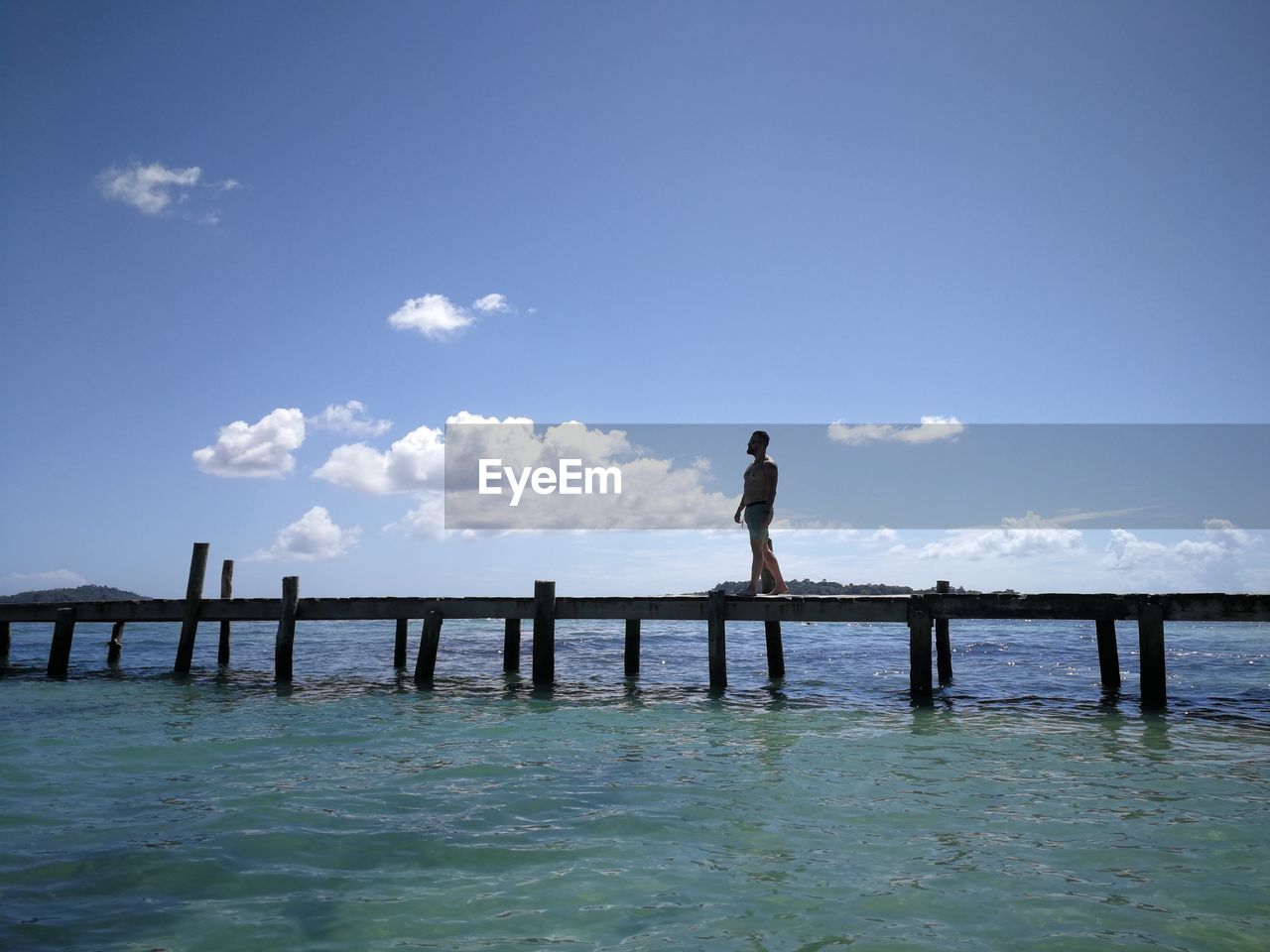 sky, water, ocean, sea, horizon, nature, shore, one person, full length, cloud, wave, reflection, standing, blue, beauty in nature, coast, pier, holiday, vacation, adult, scenics - nature, trip, leisure activity, day, body of water, tranquility, architecture, men, lifestyles, bay, land, outdoors, tranquil scene, travel, silhouette, beach, women, travel destinations, copy space, built structure, idyllic, rear view, bridge, environment, horizon over water, sunlight, wood, motion