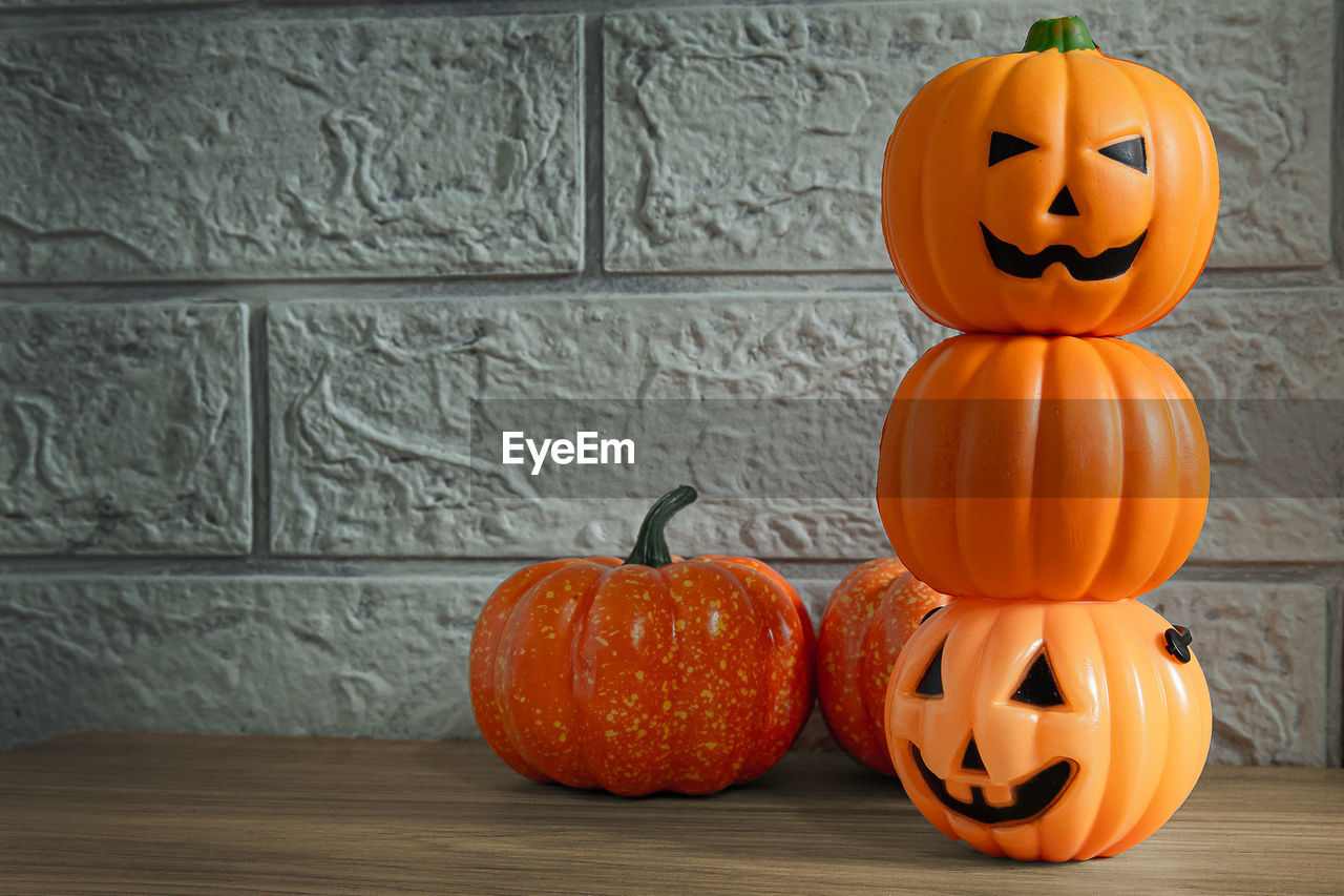 PUMPKINS ON TABLE AGAINST ORANGE WALL