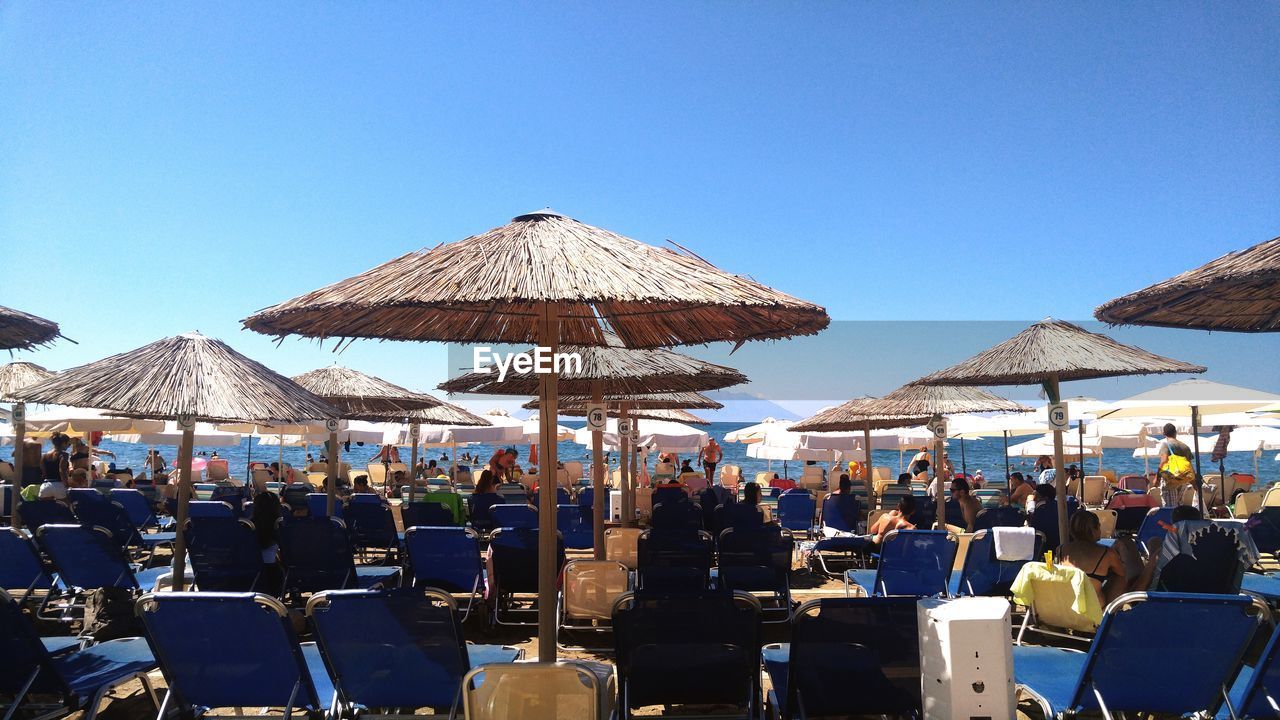 Group of people in restaurant at beach against clear blue sky