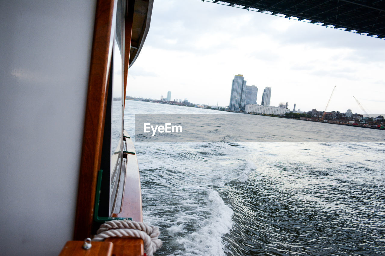 Boat sailing on river against city