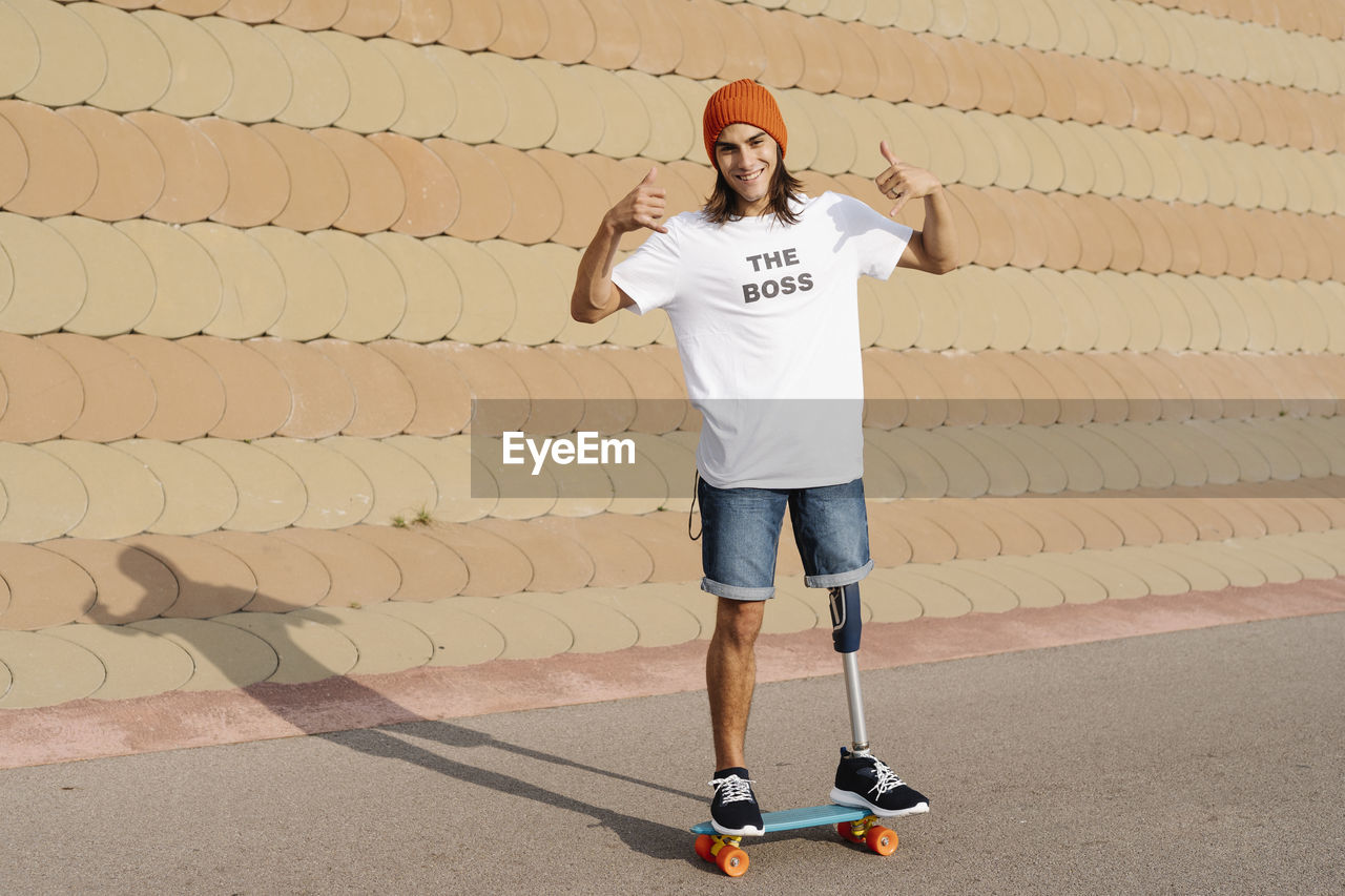 Young disabled man standing on skateboard at sports court