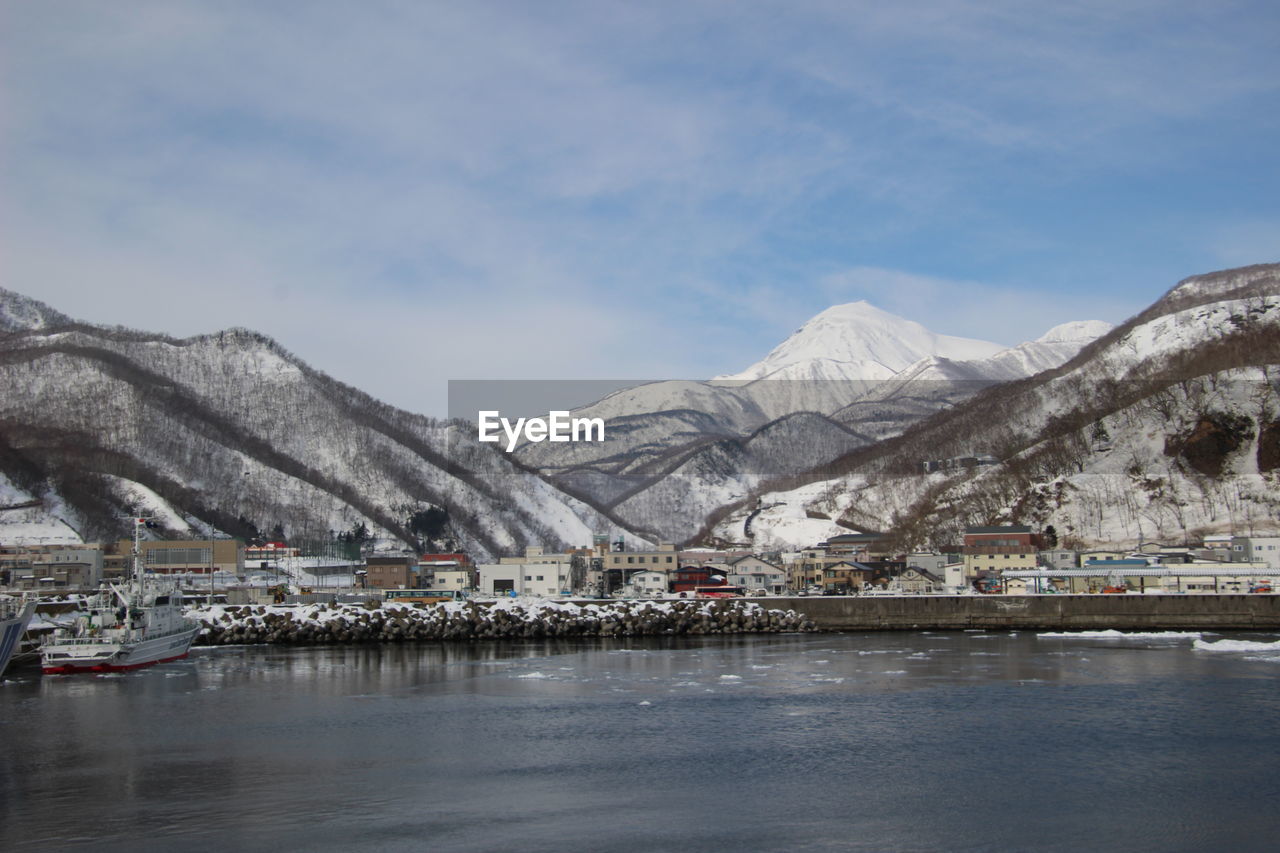 Scenic view of lake by snowcapped mountains against sky