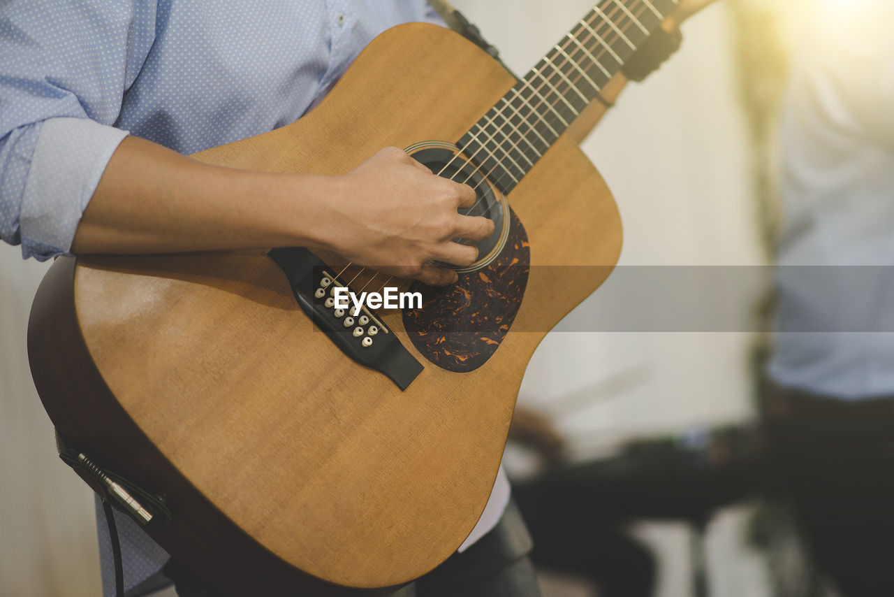 MIDSECTION OF MAN PLAYING GUITAR AT MUSIC CONCERT