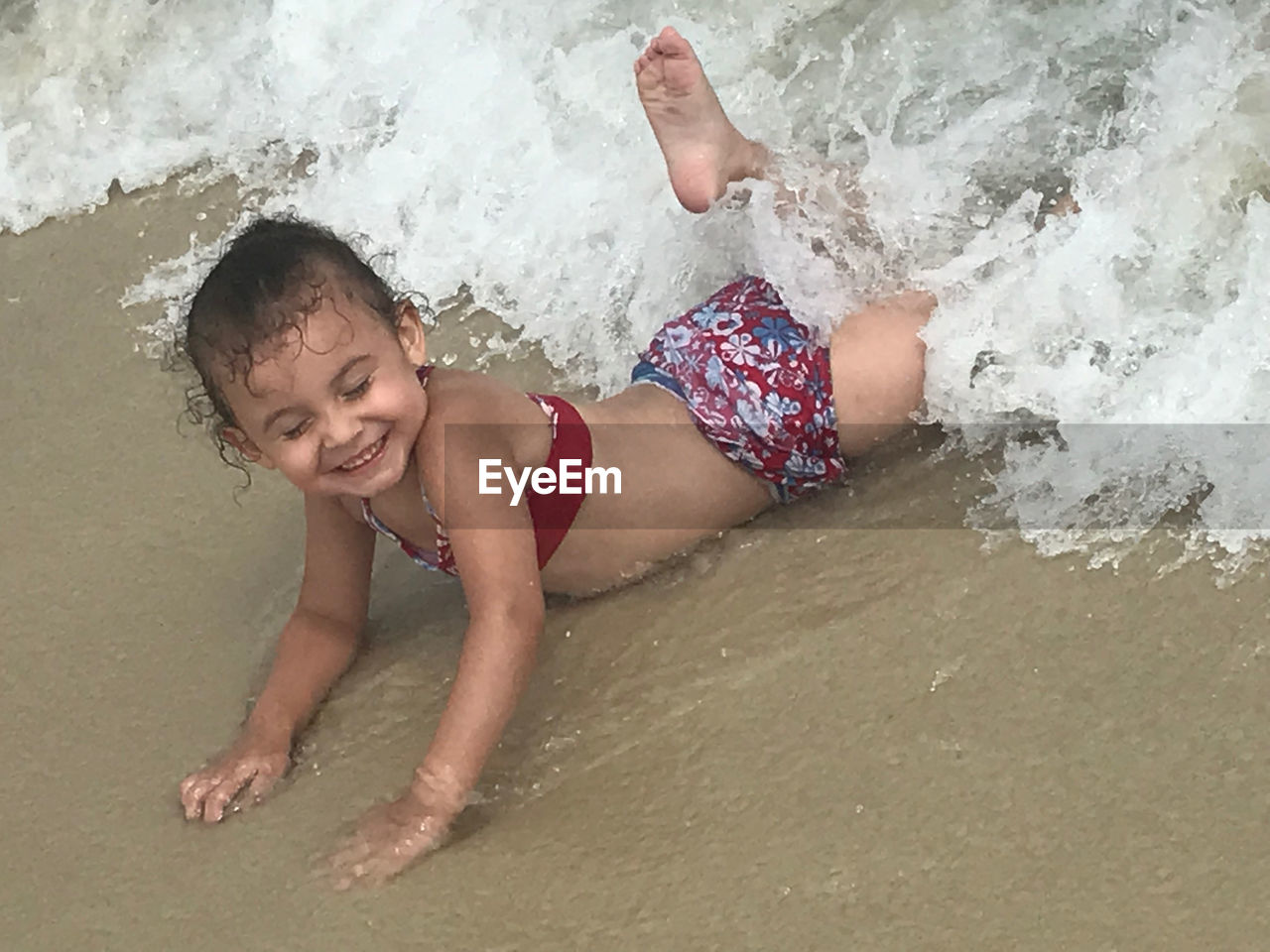 PORTRAIT OF SMILING BOY LYING ON BEACH
