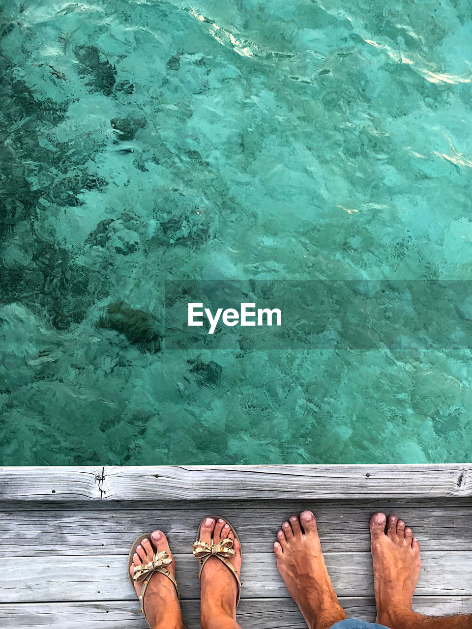 Low section of couple standing by sea