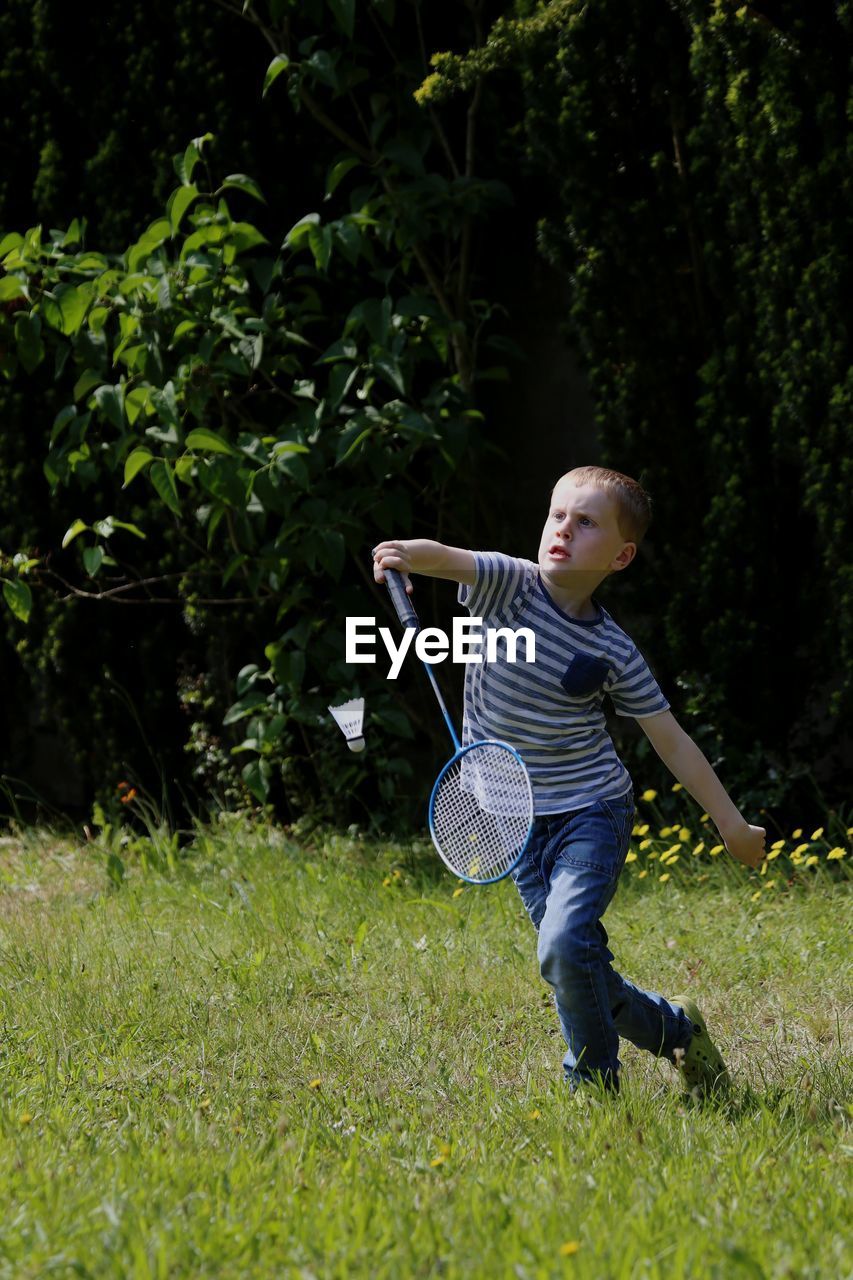 Full length of boy playing badminton in yard
