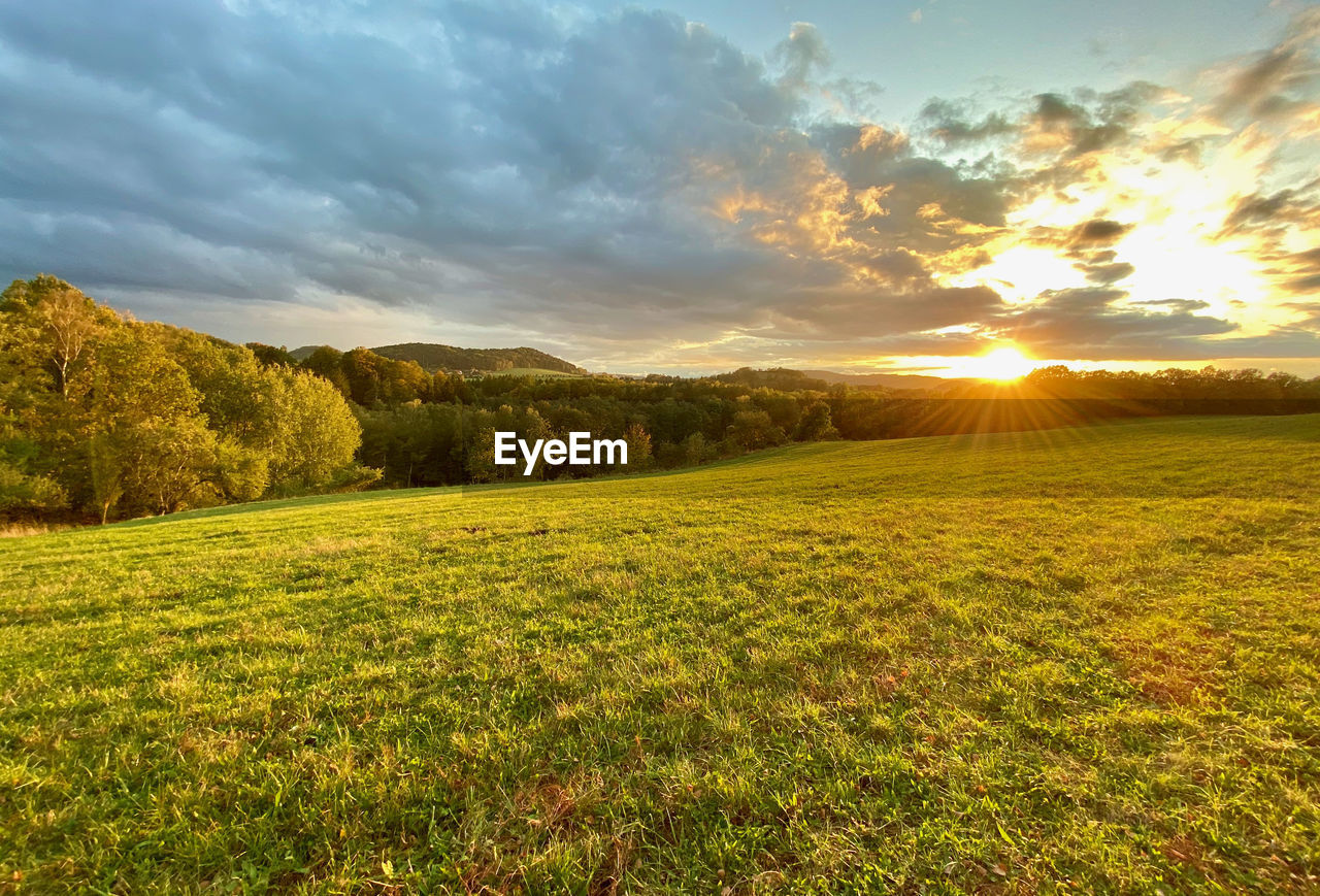 SCENIC VIEW OF FIELD AGAINST SKY AT SUNSET