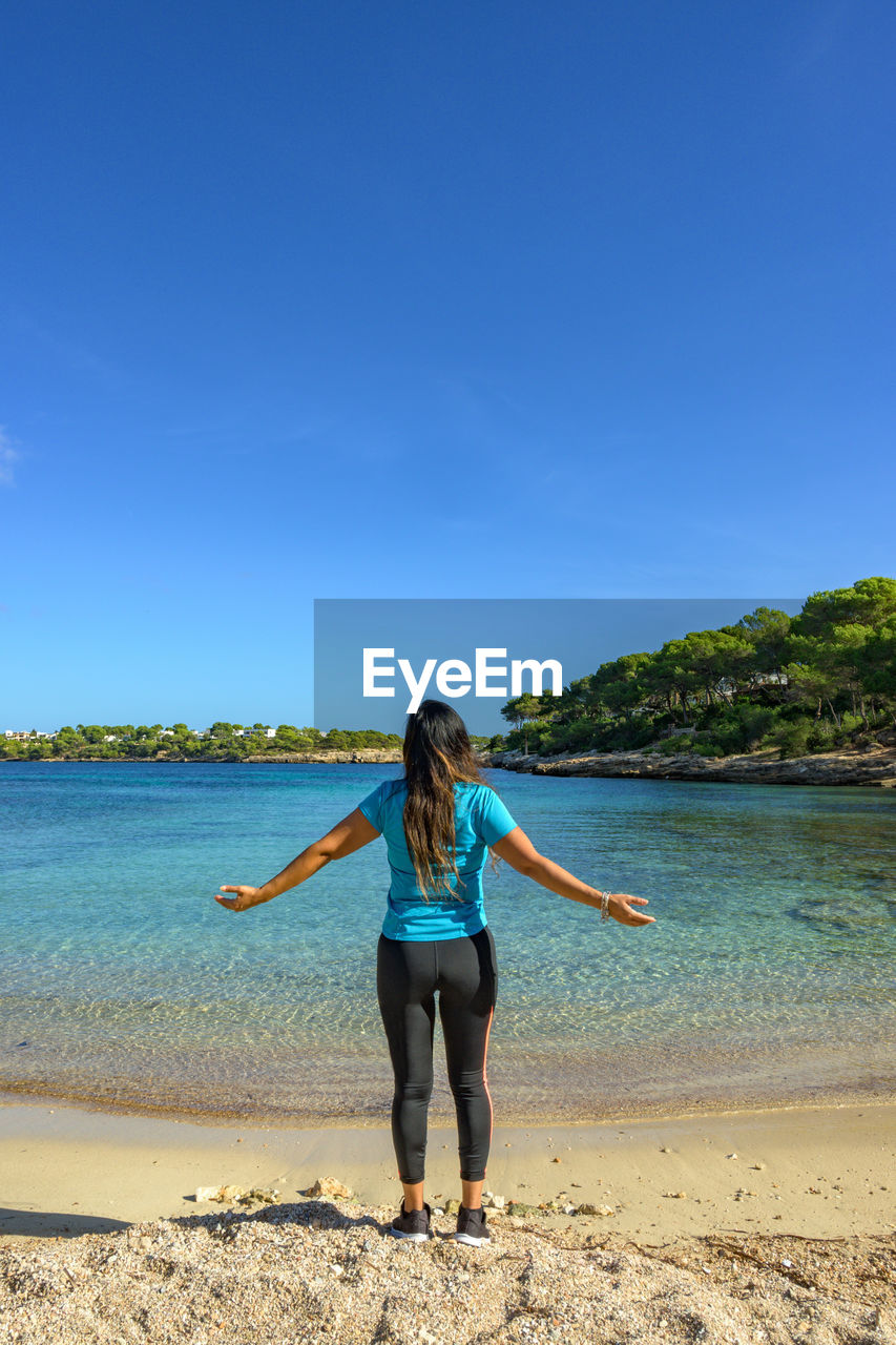 Latina woman, on the shore of the beach looking at the sea breathing deeply