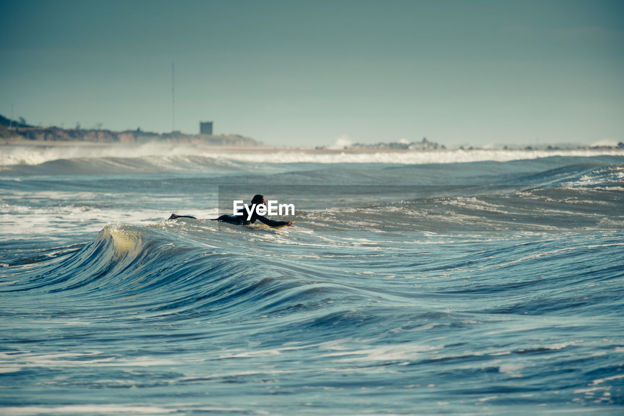 MAN SURFING ON SEA AGAINST SKY