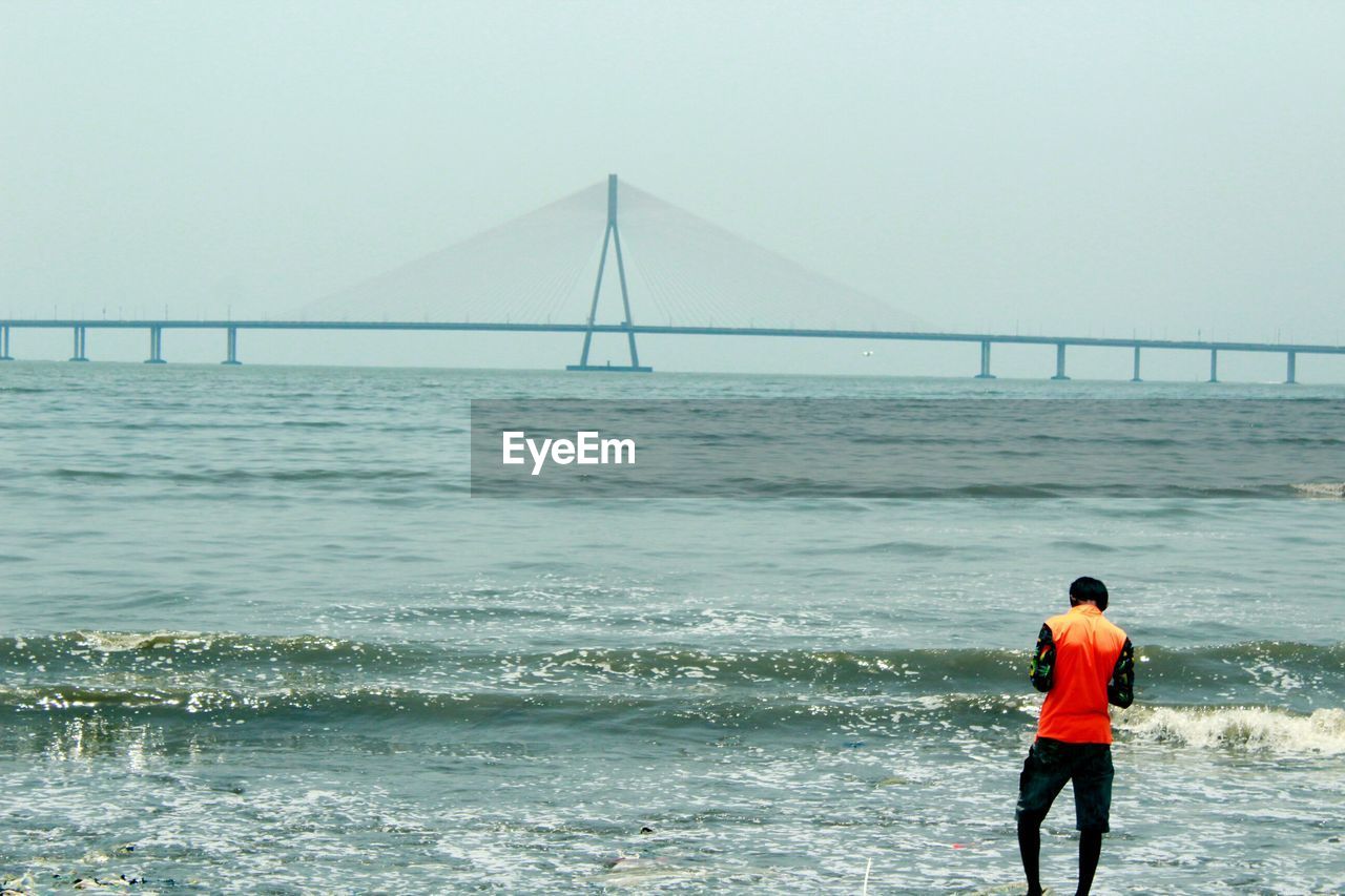 Rear view of man standing by suspension bridge