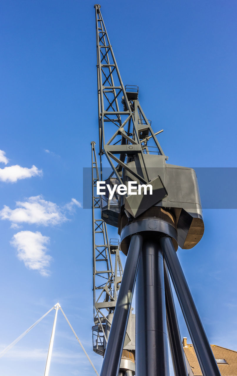 sky, mast, architecture, blue, nature, industry, built structure, cloud, power generation, technology, no people, low angle view, outdoors, day, metal, wind, transportation, tower, machinery, windmill, business, environment, business finance and industry, alloy, vehicle, steel