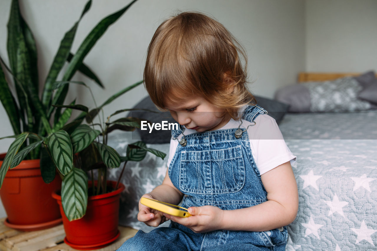 A small child at home on the couch uses a smartphone