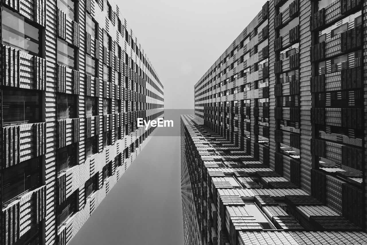 Directly below shot of modern buildings against clear sky