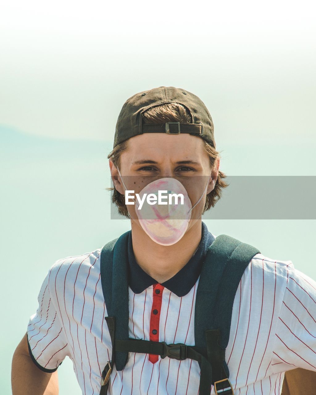 Portrait of teenage boy wearing mask against sky