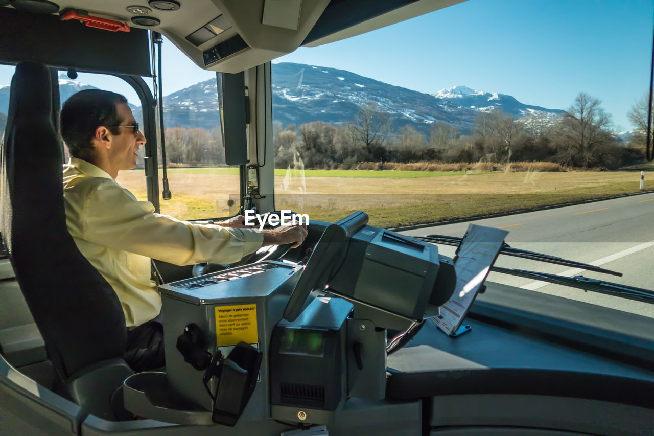 SIDE VIEW OF MAN SITTING IN BUS