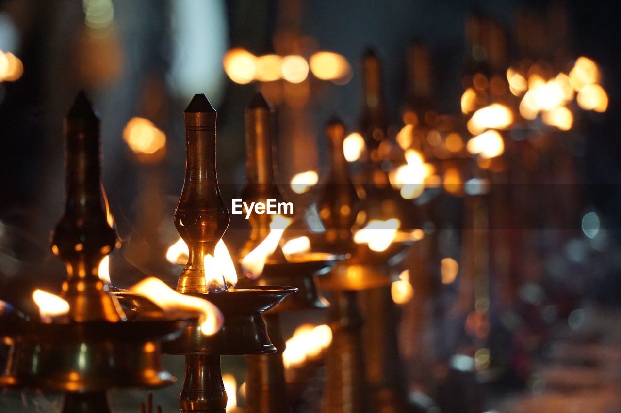 CLOSE-UP OF ILLUMINATED CANDLES IN TEMPLE