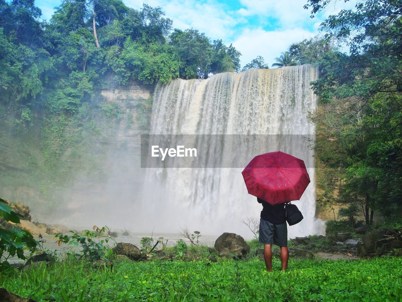 Full length of man standing against waterfall