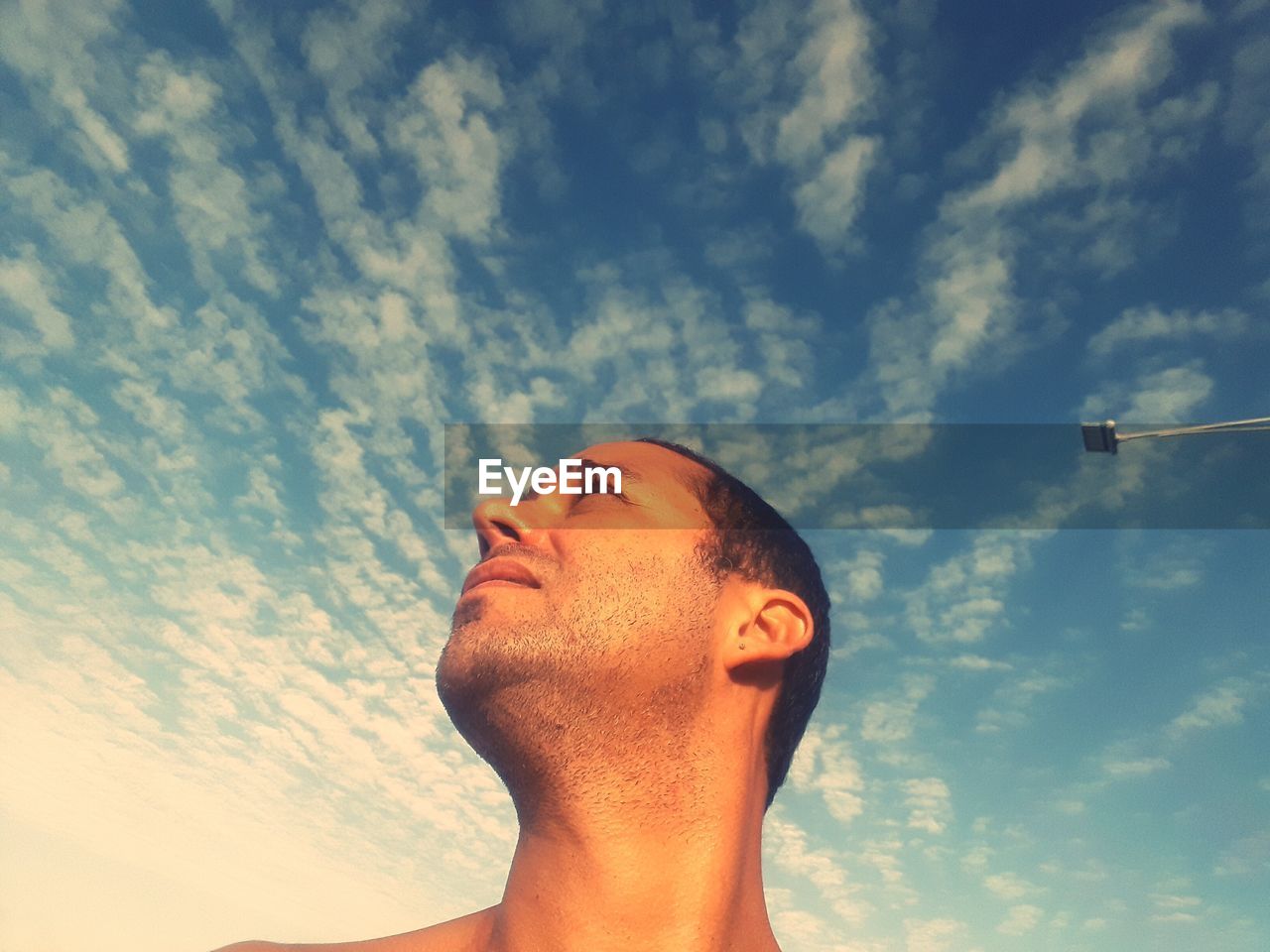 Low angle view of man looking up against cloudy sky