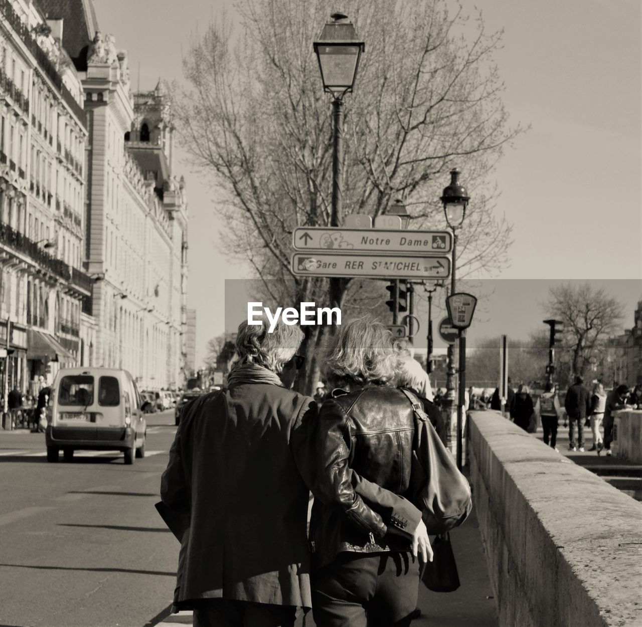 REAR VIEW OF PEOPLE TRAVELING ON STREET IN CITY