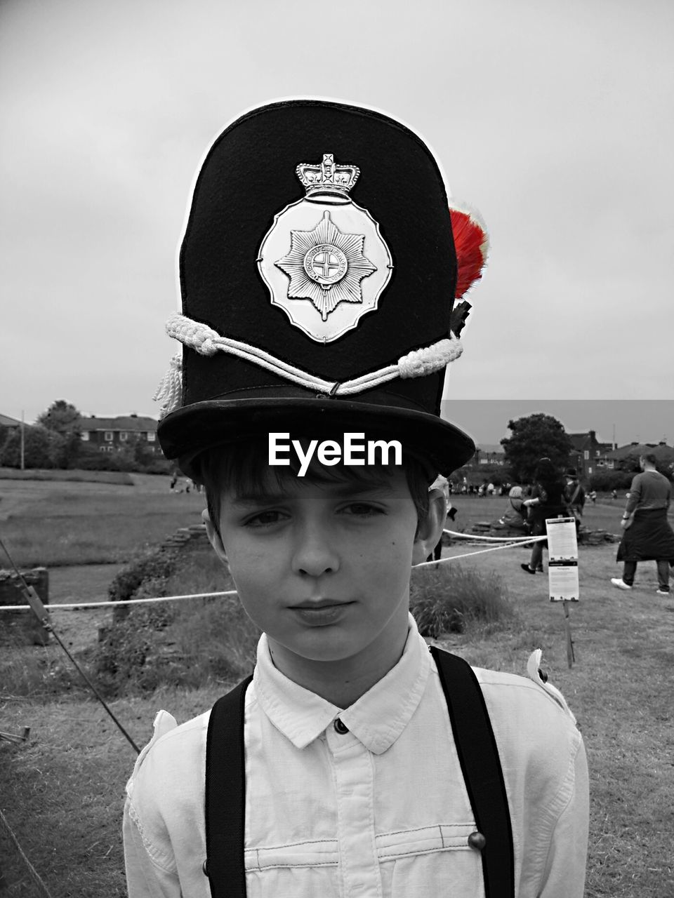 Portrait of boy wearing hat standing on field against sky