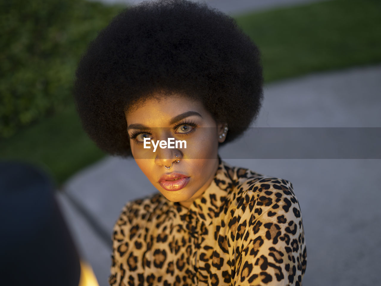 Pensive gorgeous african american female with afro hair and piercing thoughtfully looking at camera during twilight