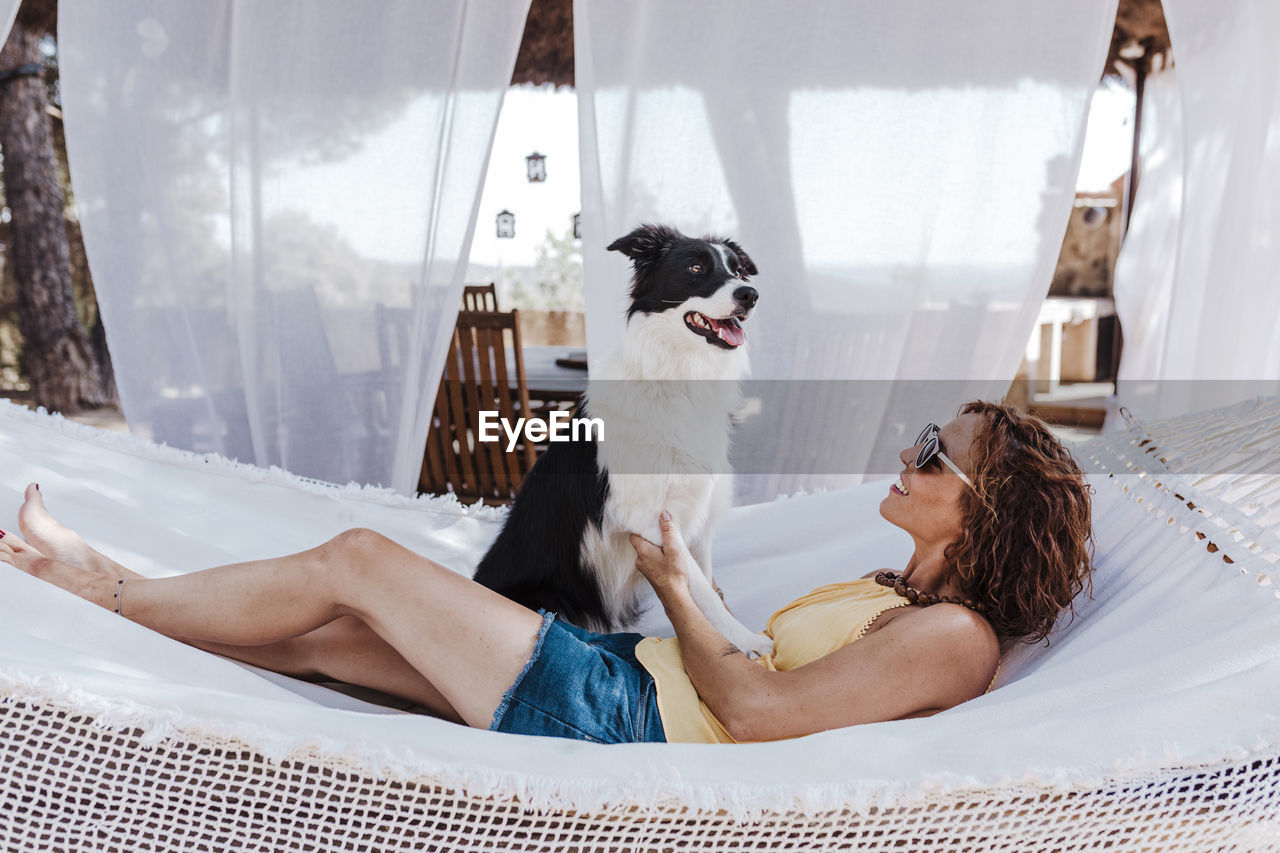 Smiling woman with dog sitting on hammock