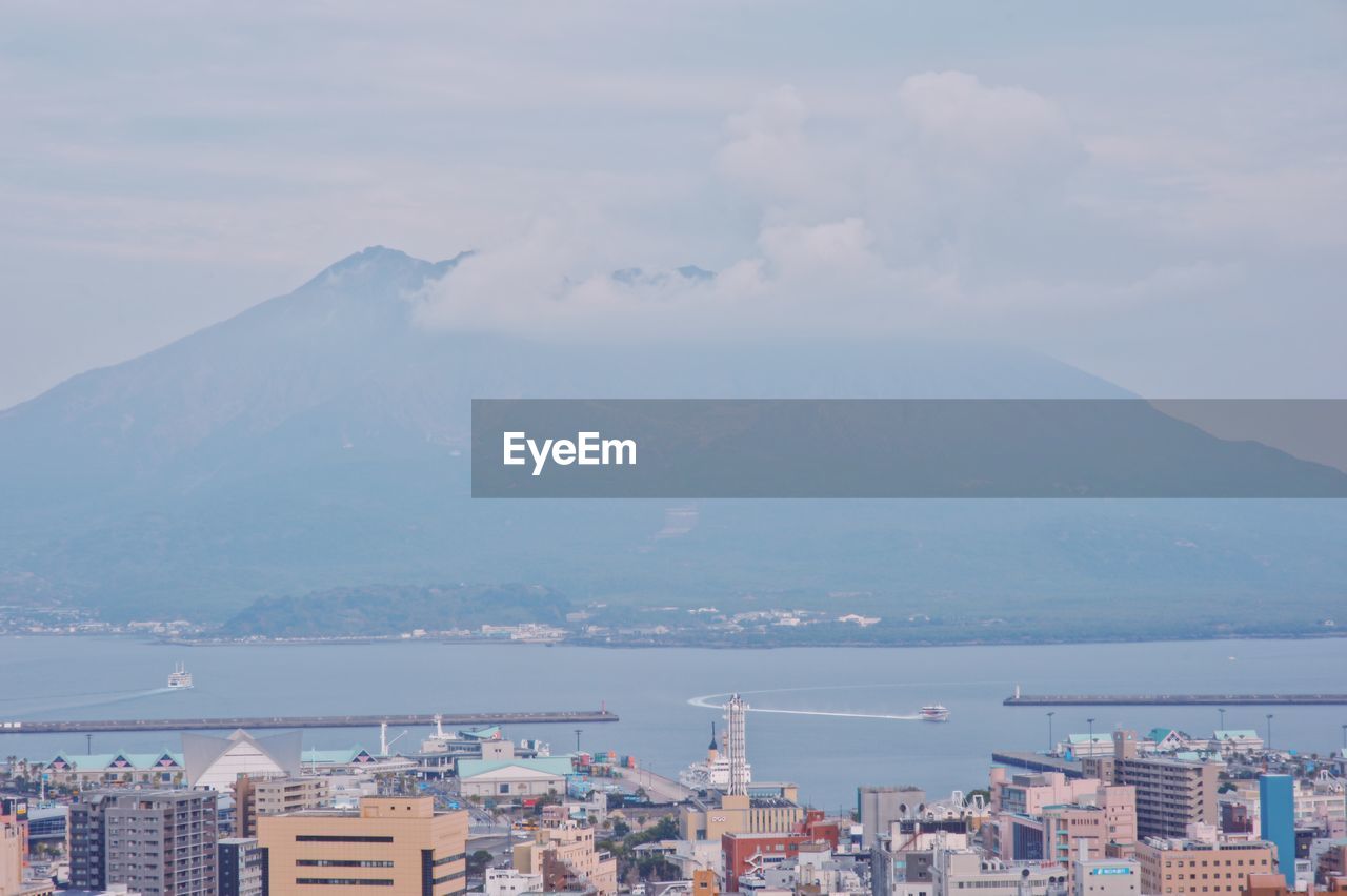 Aerial view of city by sea against sky