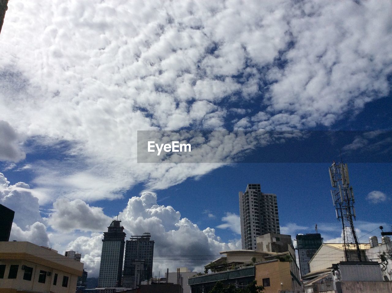 Low angle view of buildings in city against cloudy sky