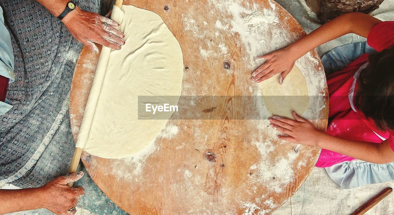 Directly above shot of mother and daughter rolling dough