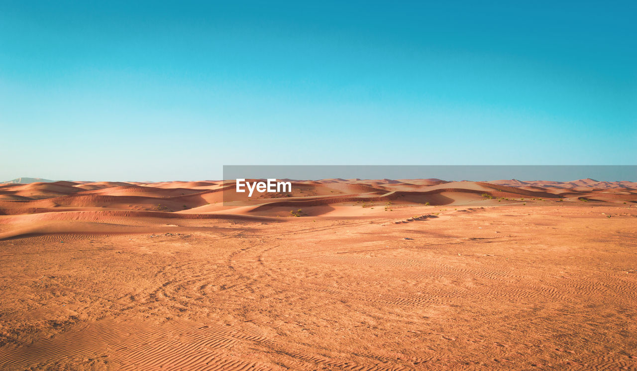 Scenic view of desert against clear blue sky