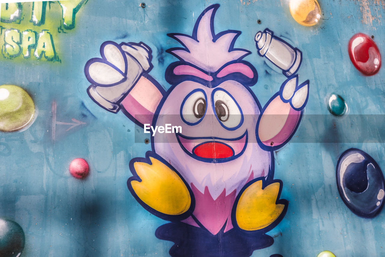 CLOSE-UP OF MULTI COLORED WALL WITH GRAFFITI