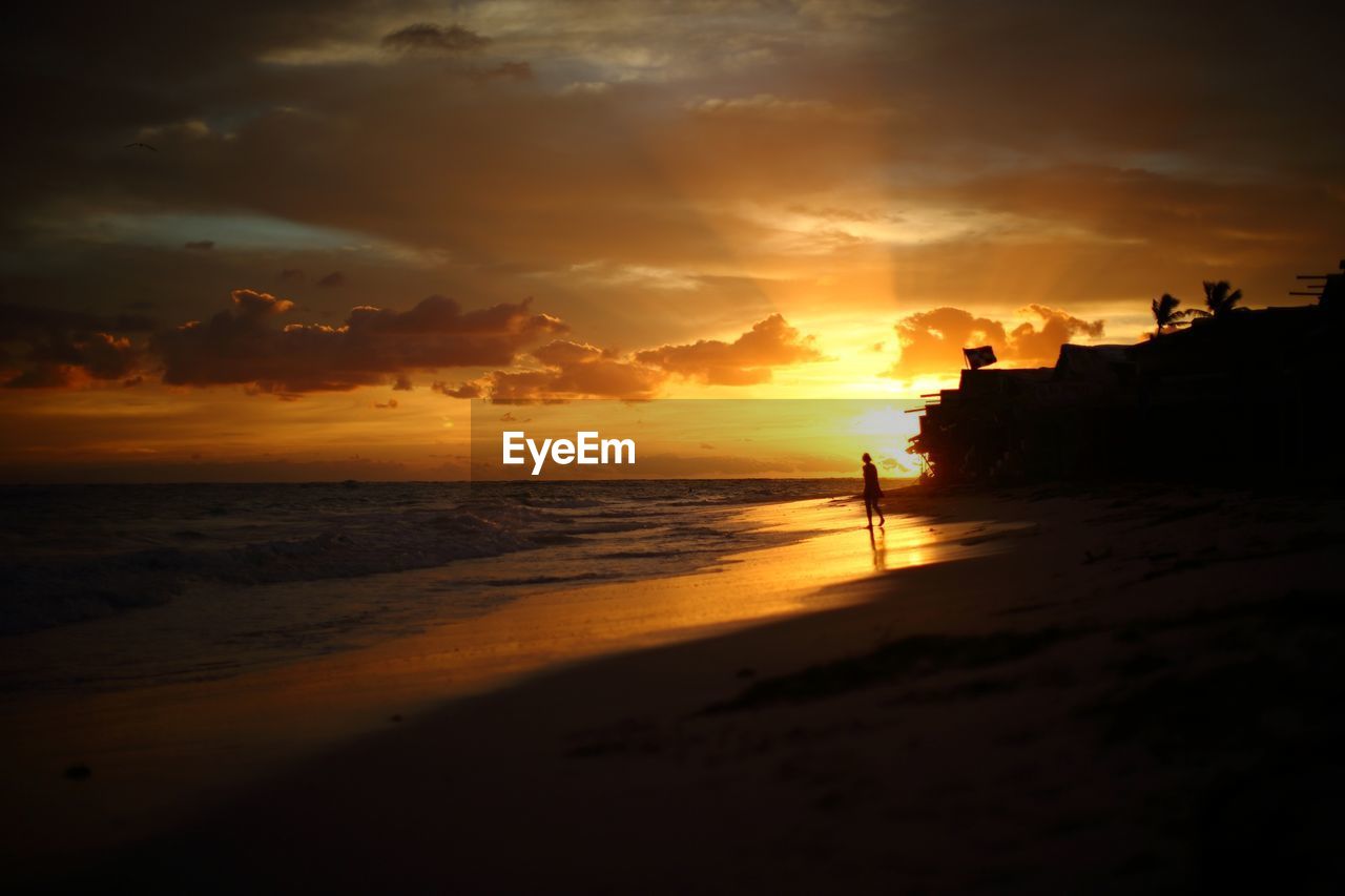 Scenic view of beach against cloudy sky at sunset