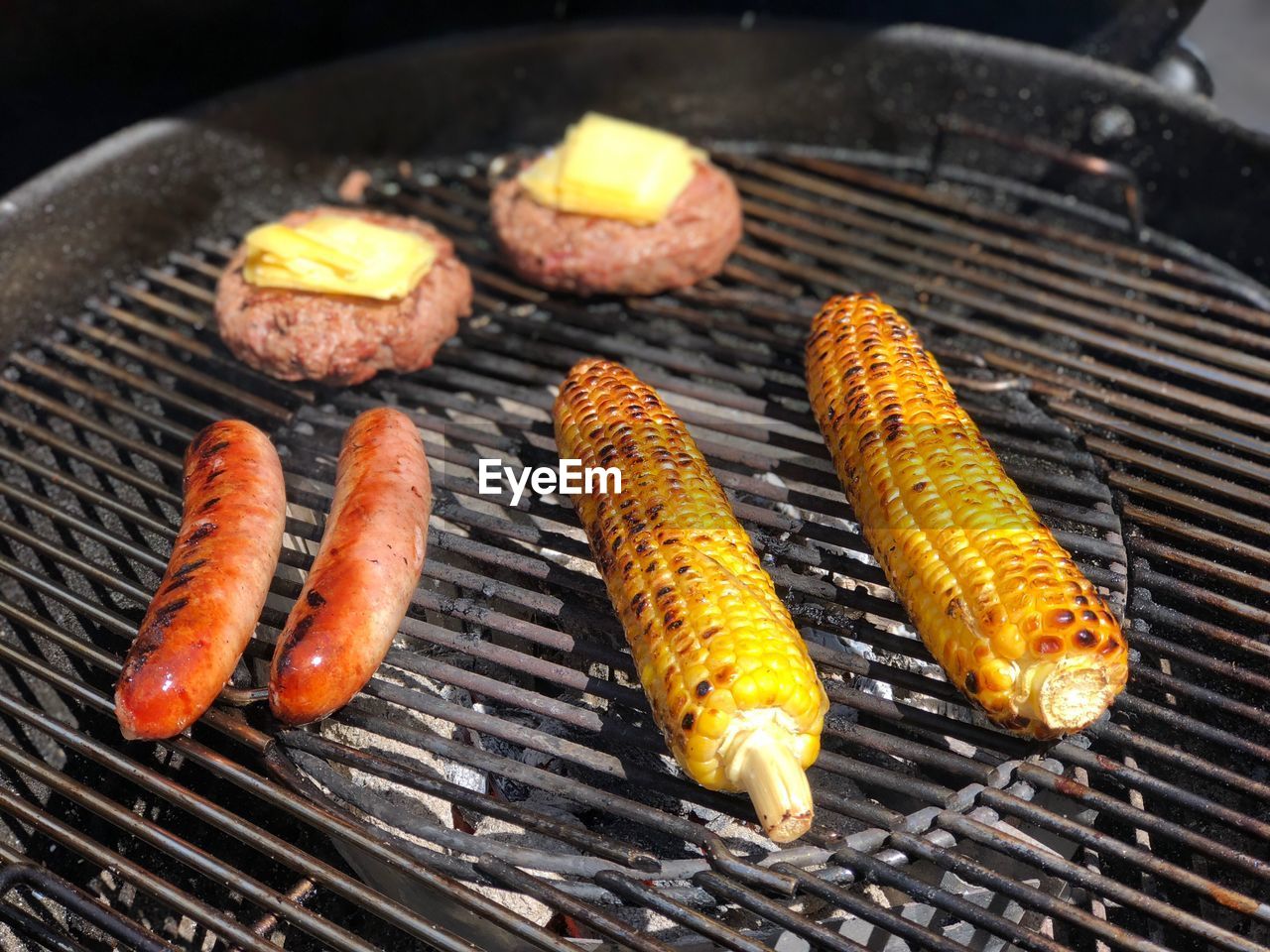 High angle view of meat and corns on barbecue grill