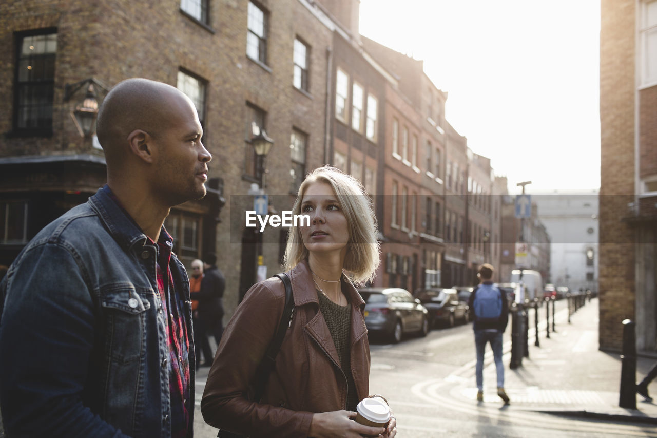 Young woman looking at man while walking on city street