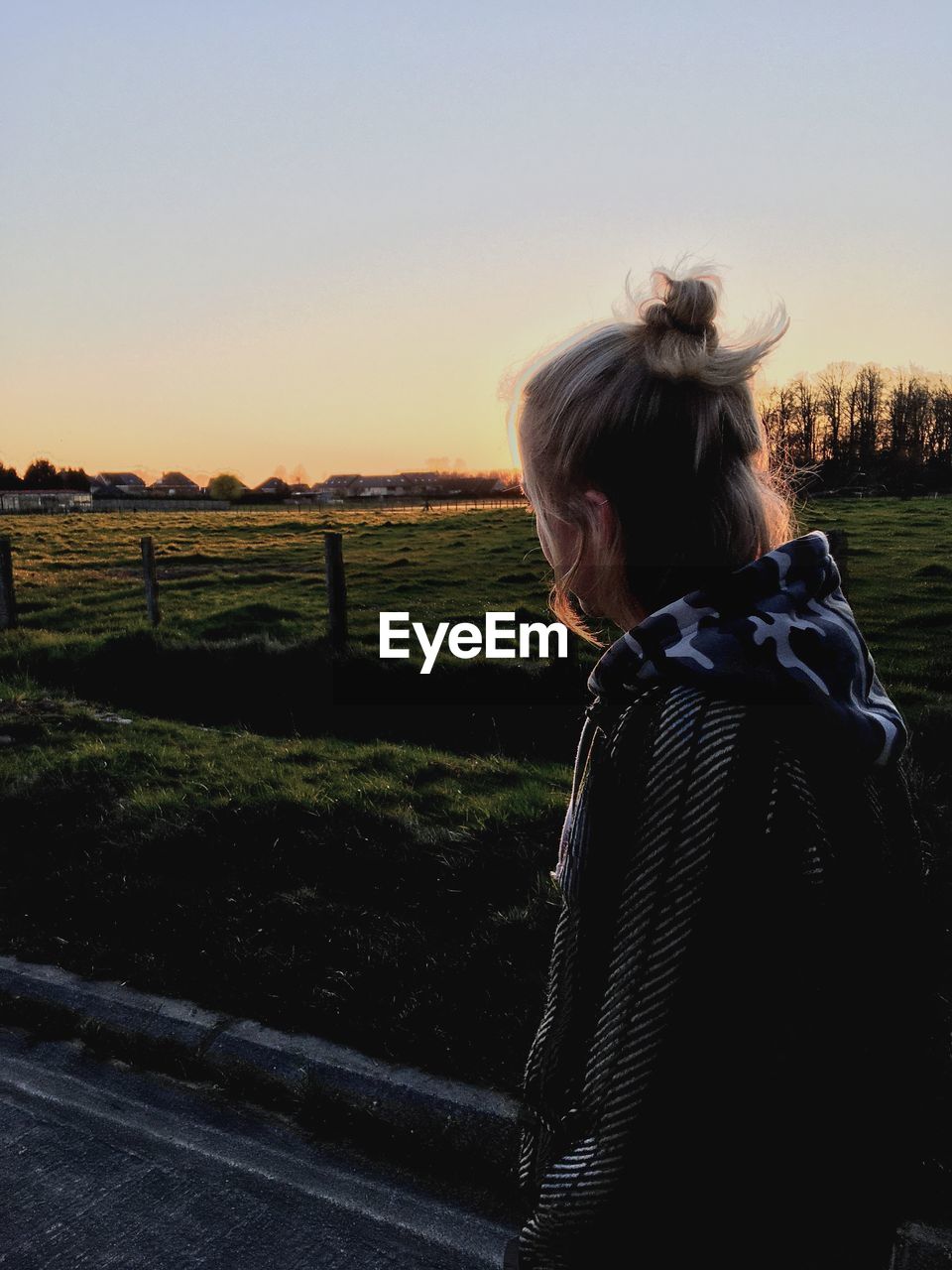 REAR VIEW OF WOMAN LOOKING AT FIELD AGAINST SKY