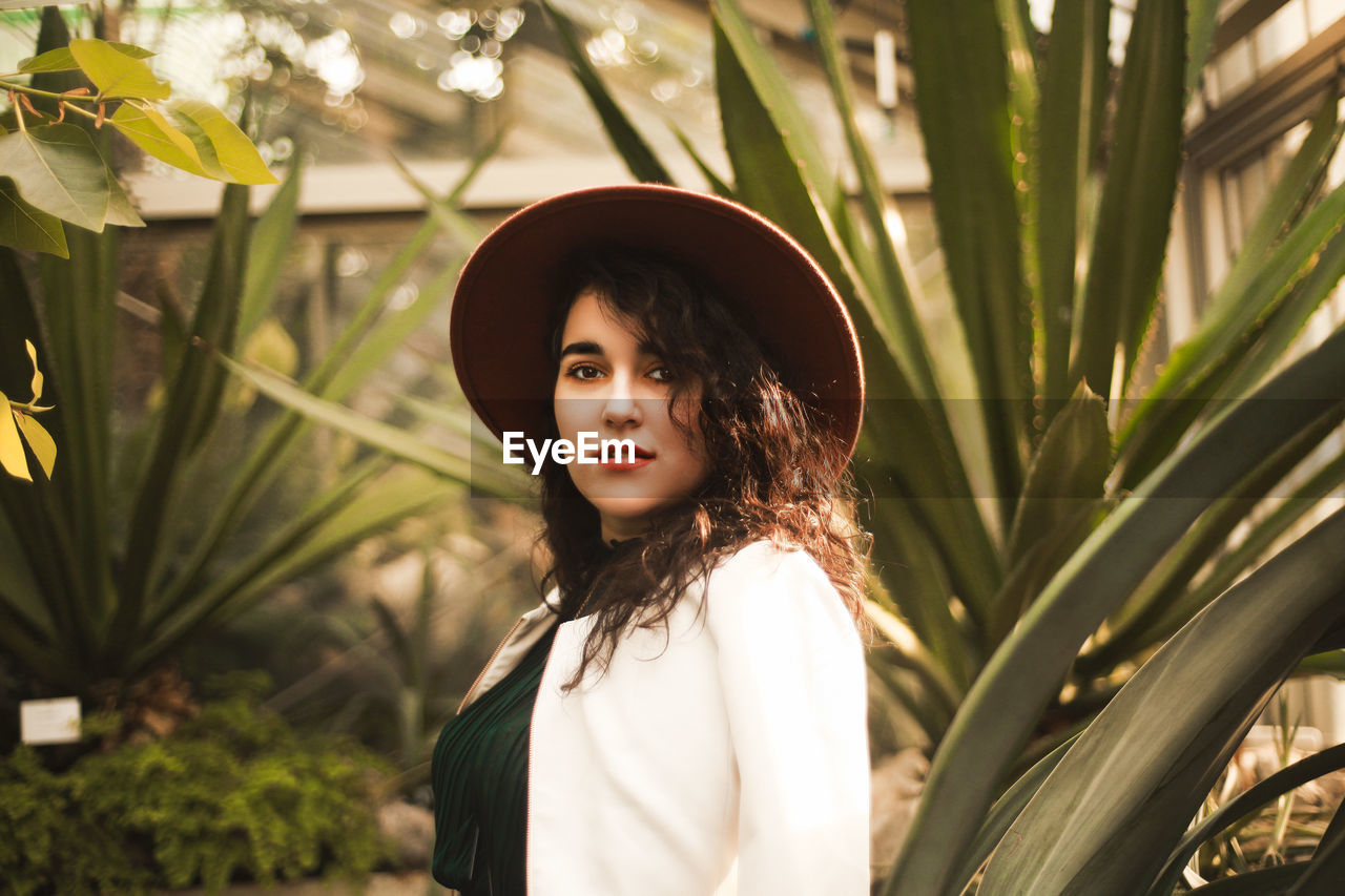 Portrait of beautiful young woman standing against plants