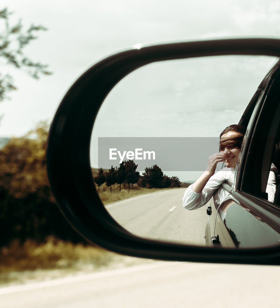 Reflection of woman in side-view mirror