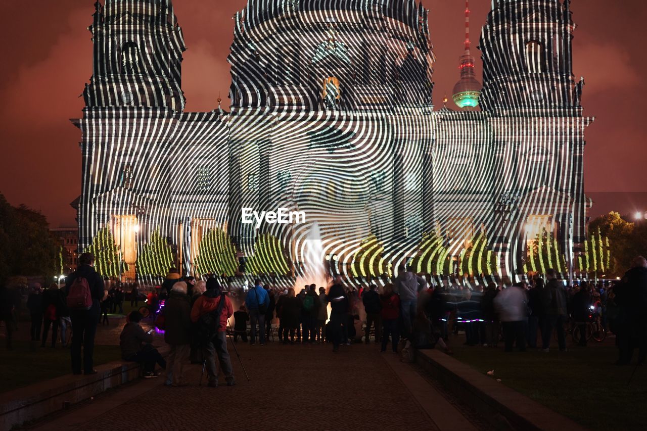 Crowd standing by projected berlin cathedral at night