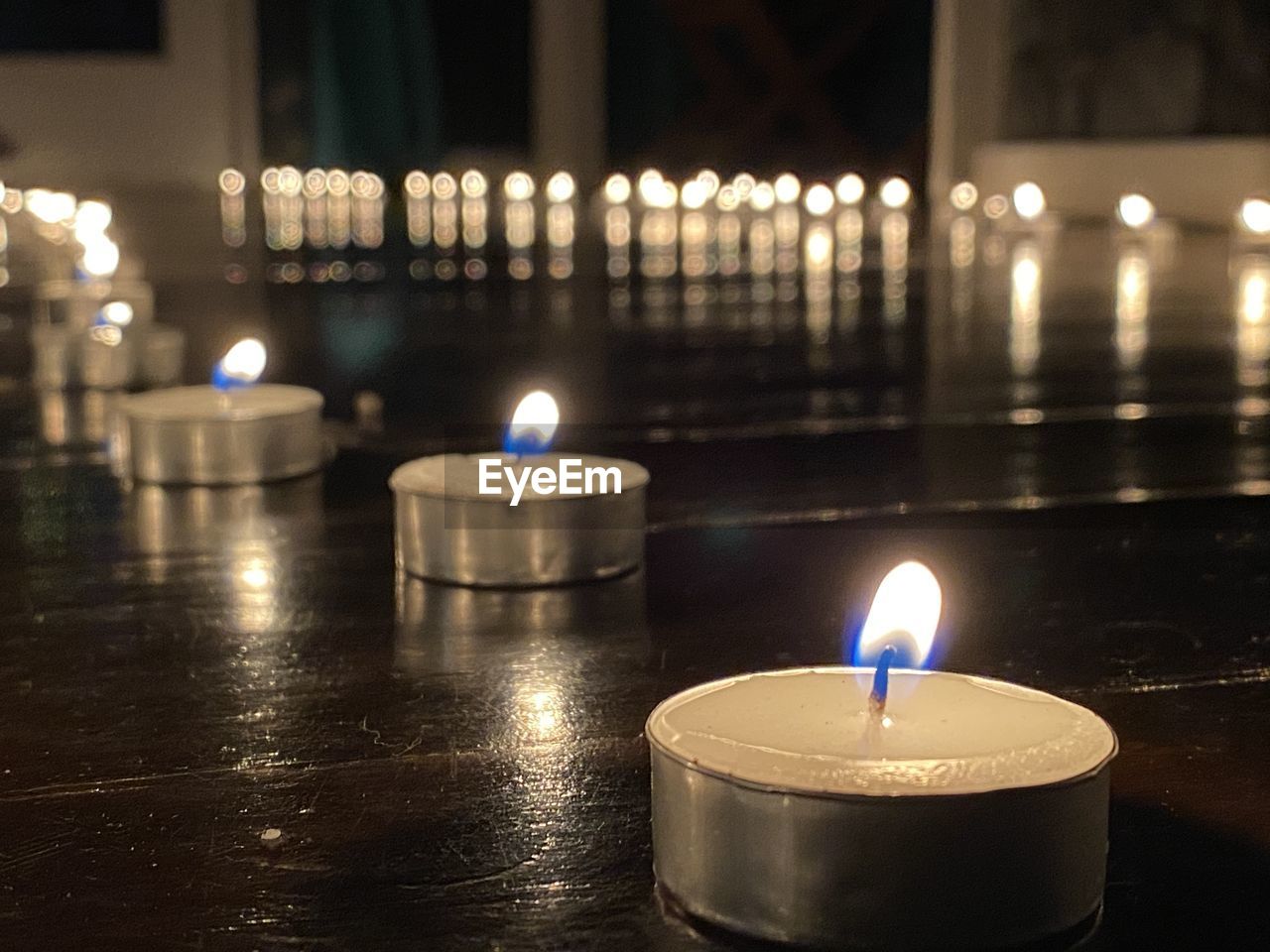 CLOSE-UP OF ILLUMINATED TEA LIGHT CANDLES IN TEMPLE