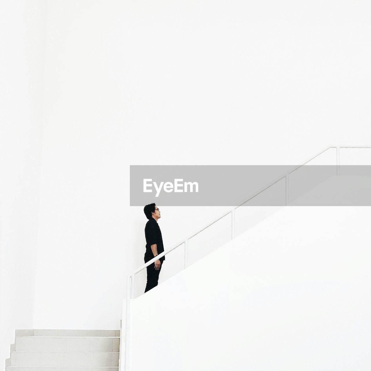 Man standing on staircase against white wall in building
