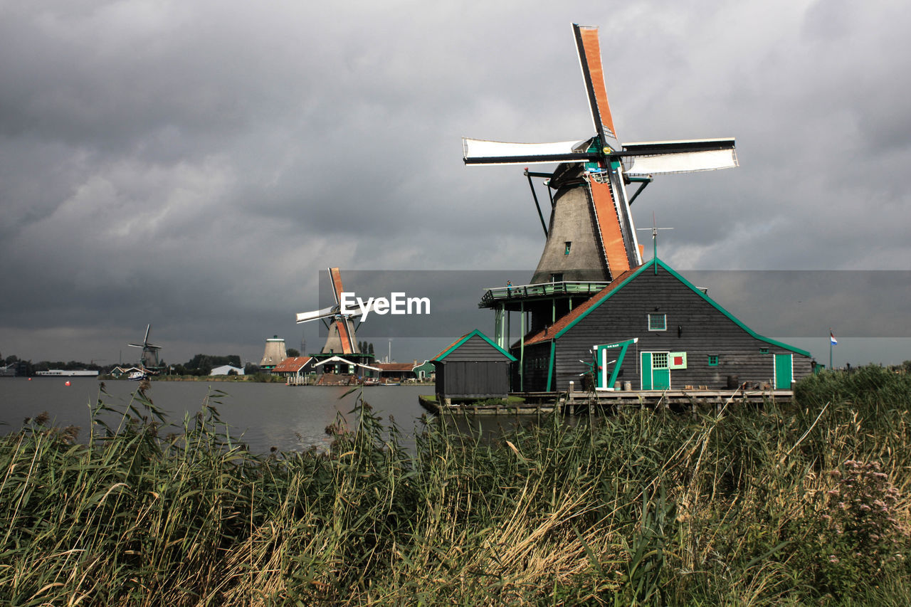 Traditional windmills by field against cloudy sky