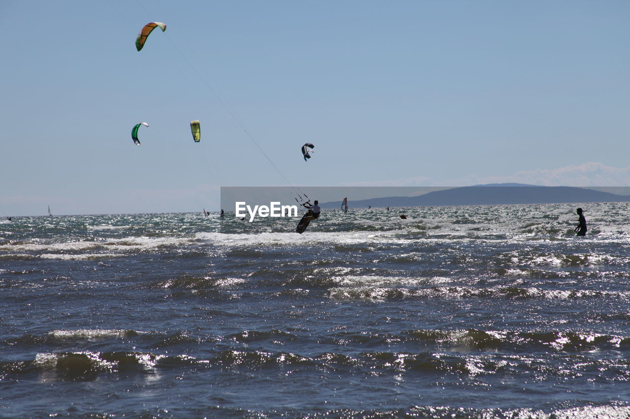 People paragliding over sea against sky