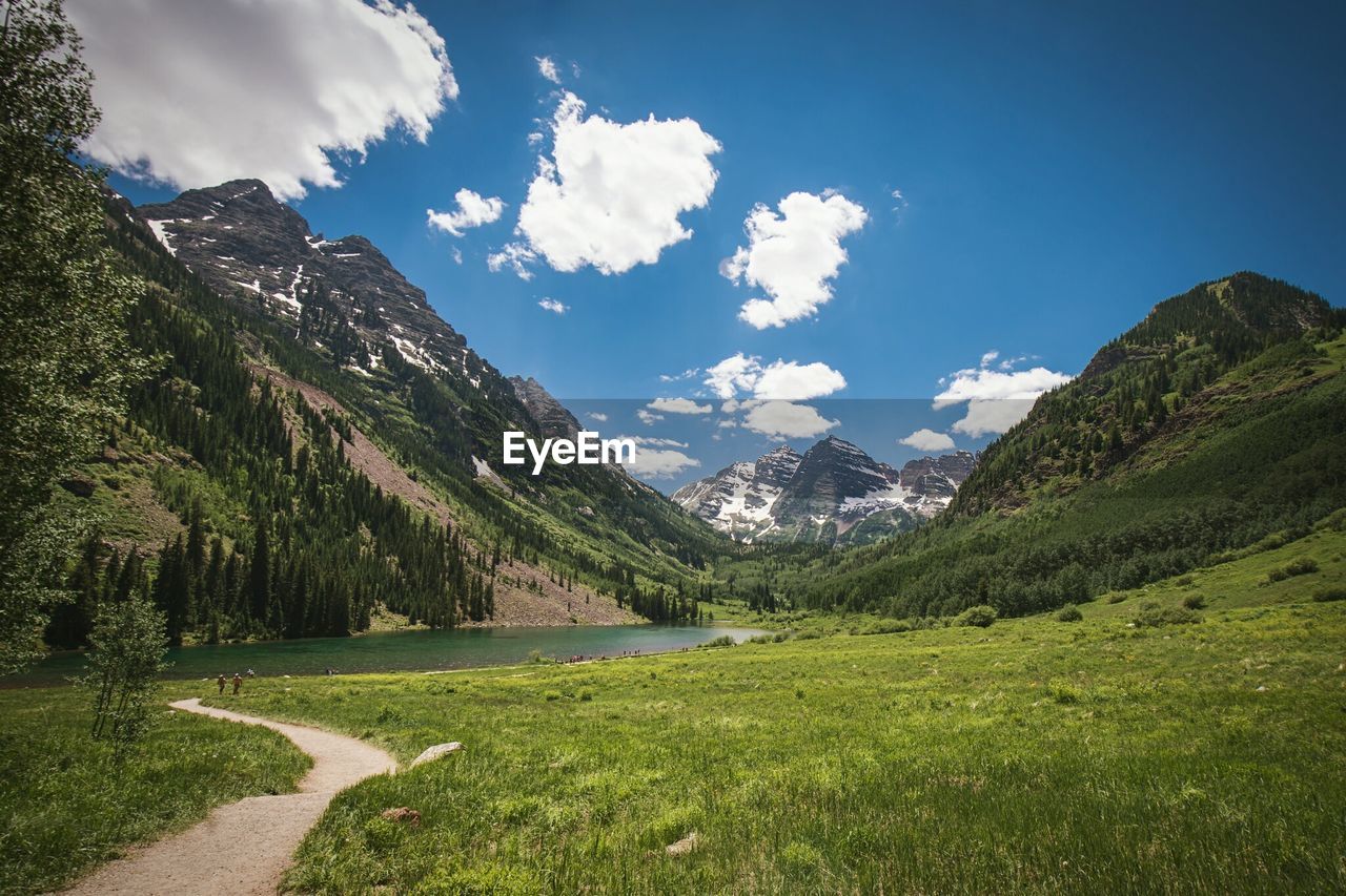 Scenic view of lake and mountains in front of grassy field against sky