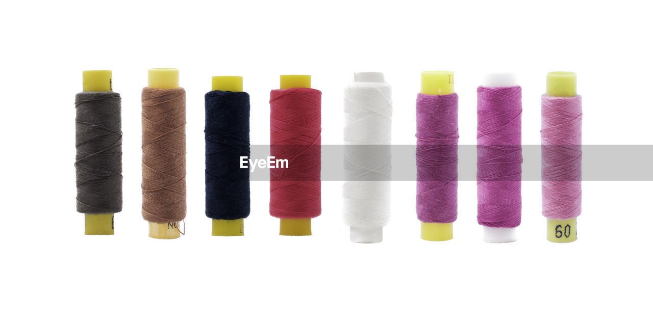 Close-up of multi colored thread spools against white background