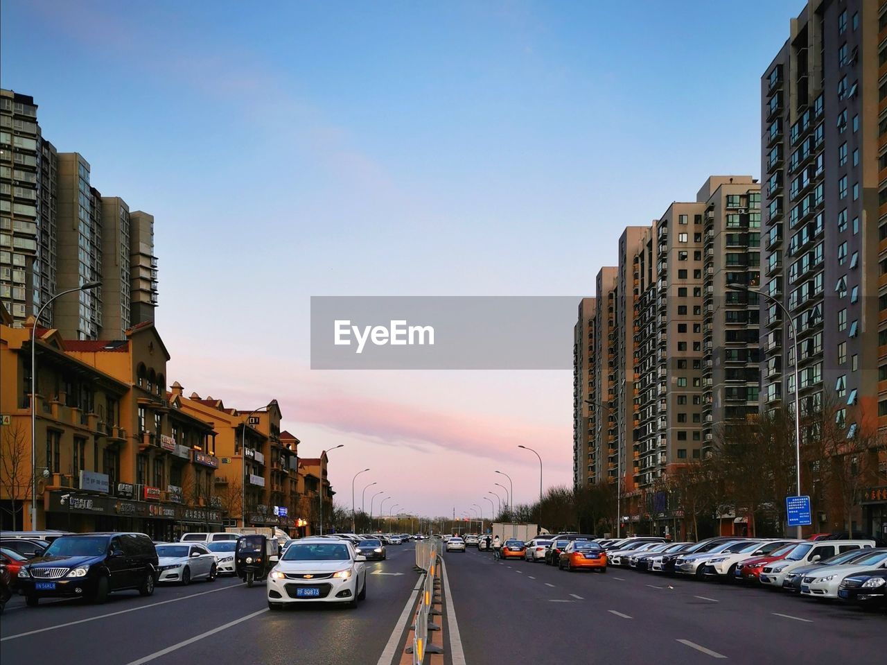 TRAFFIC ON CITY STREET AMIDST BUILDINGS AGAINST SKY