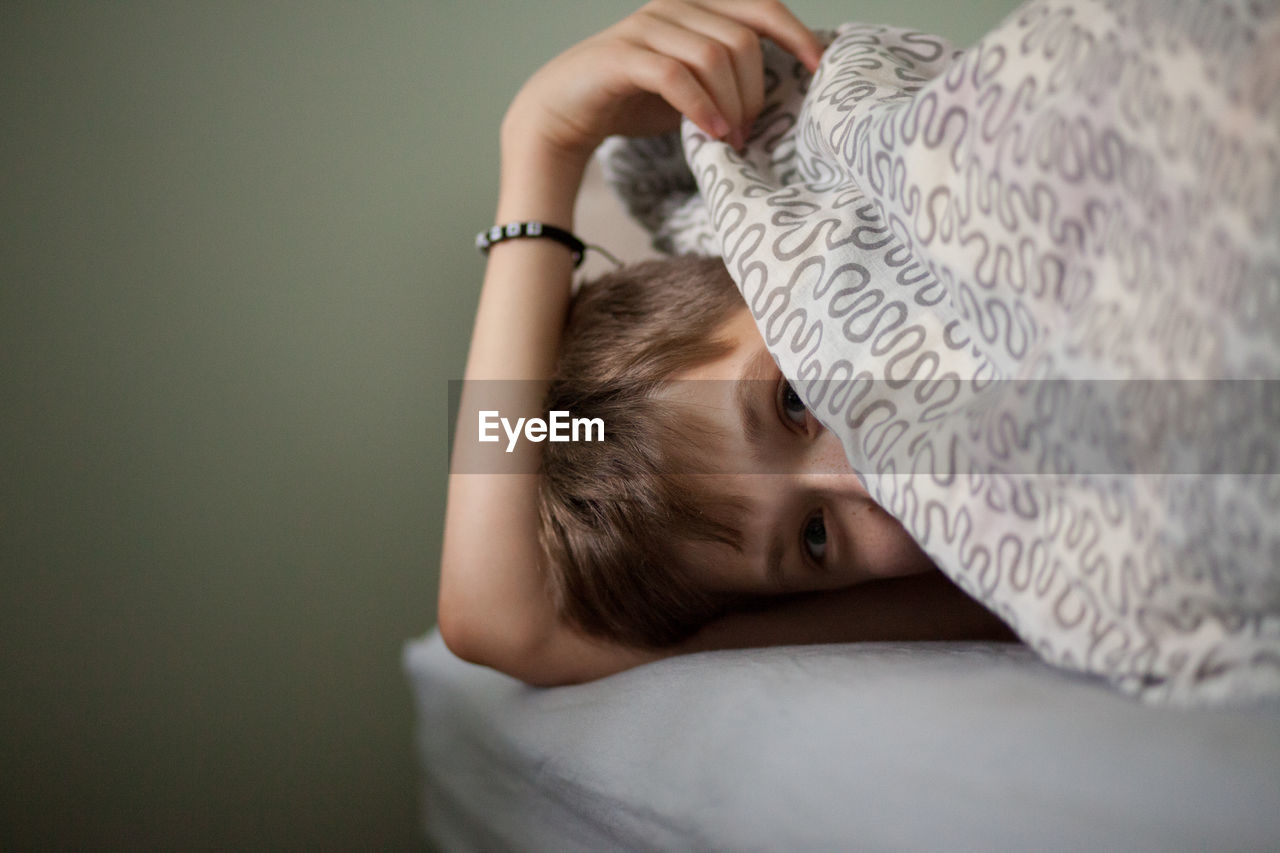 Portrait of boy lying on bed at home