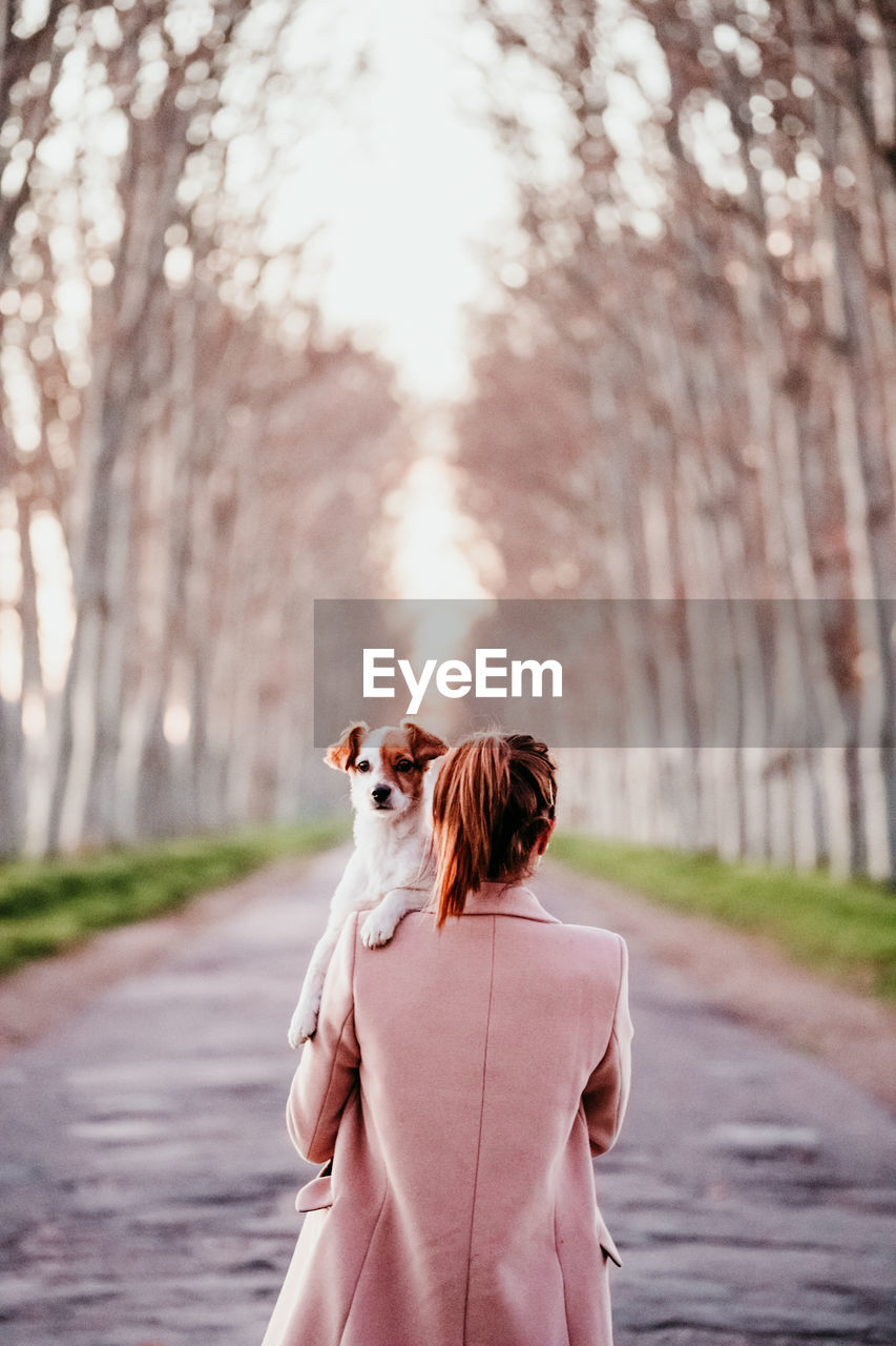 REAR VIEW OF WOMAN WITH DOG ON STREET