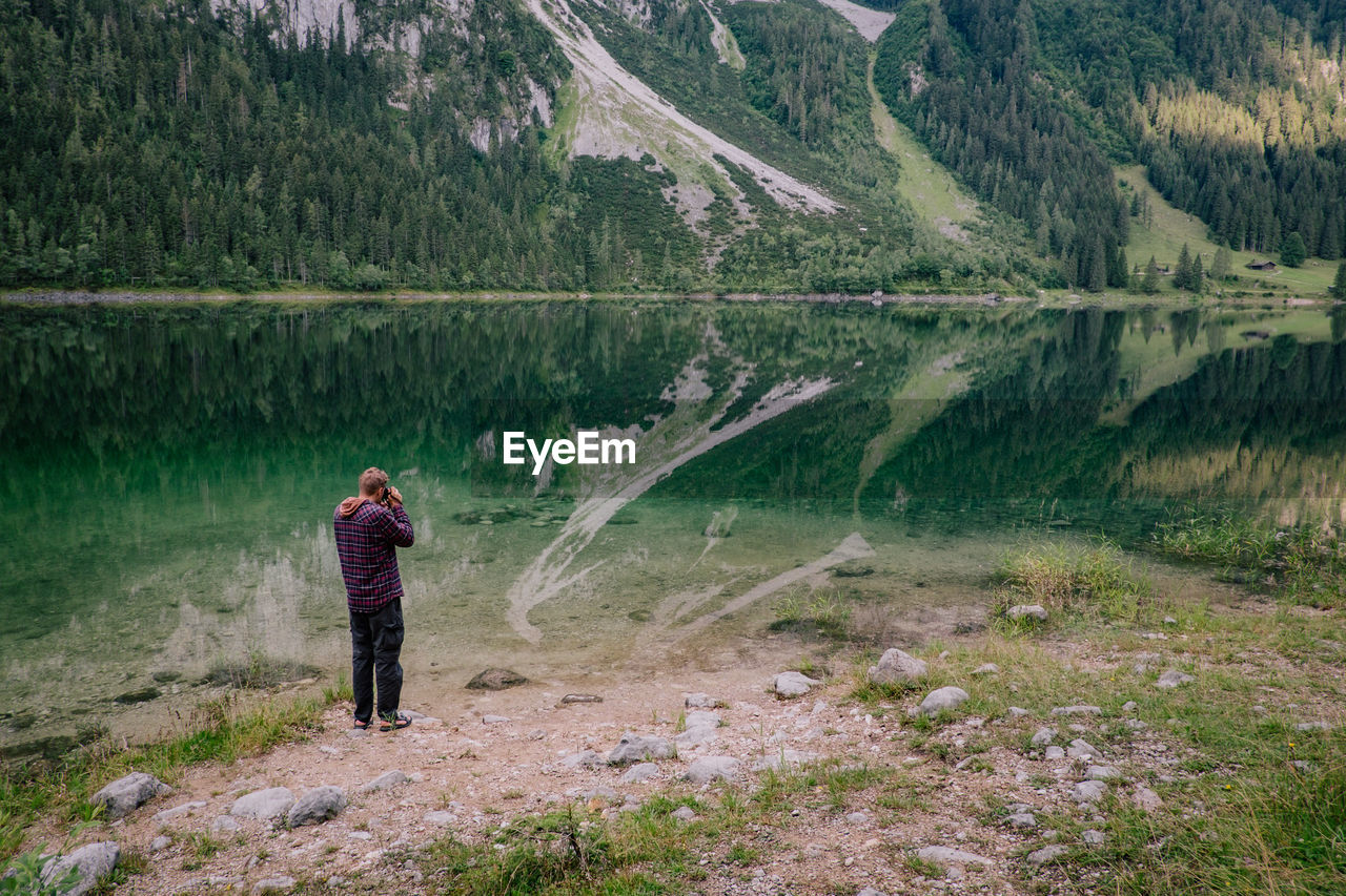 Man standing against lake and mountains