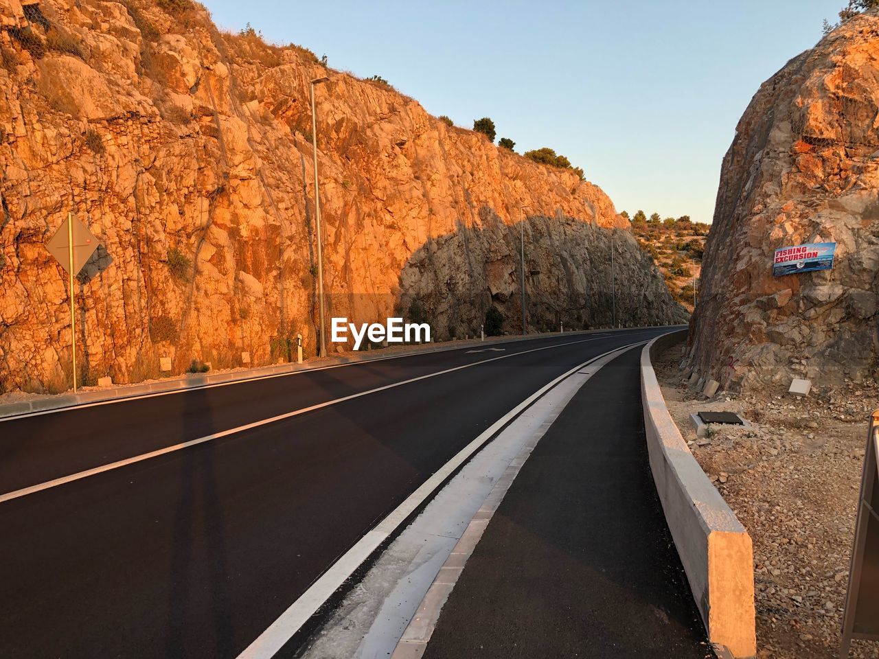 ROAD BY ROCKS AGAINST SKY