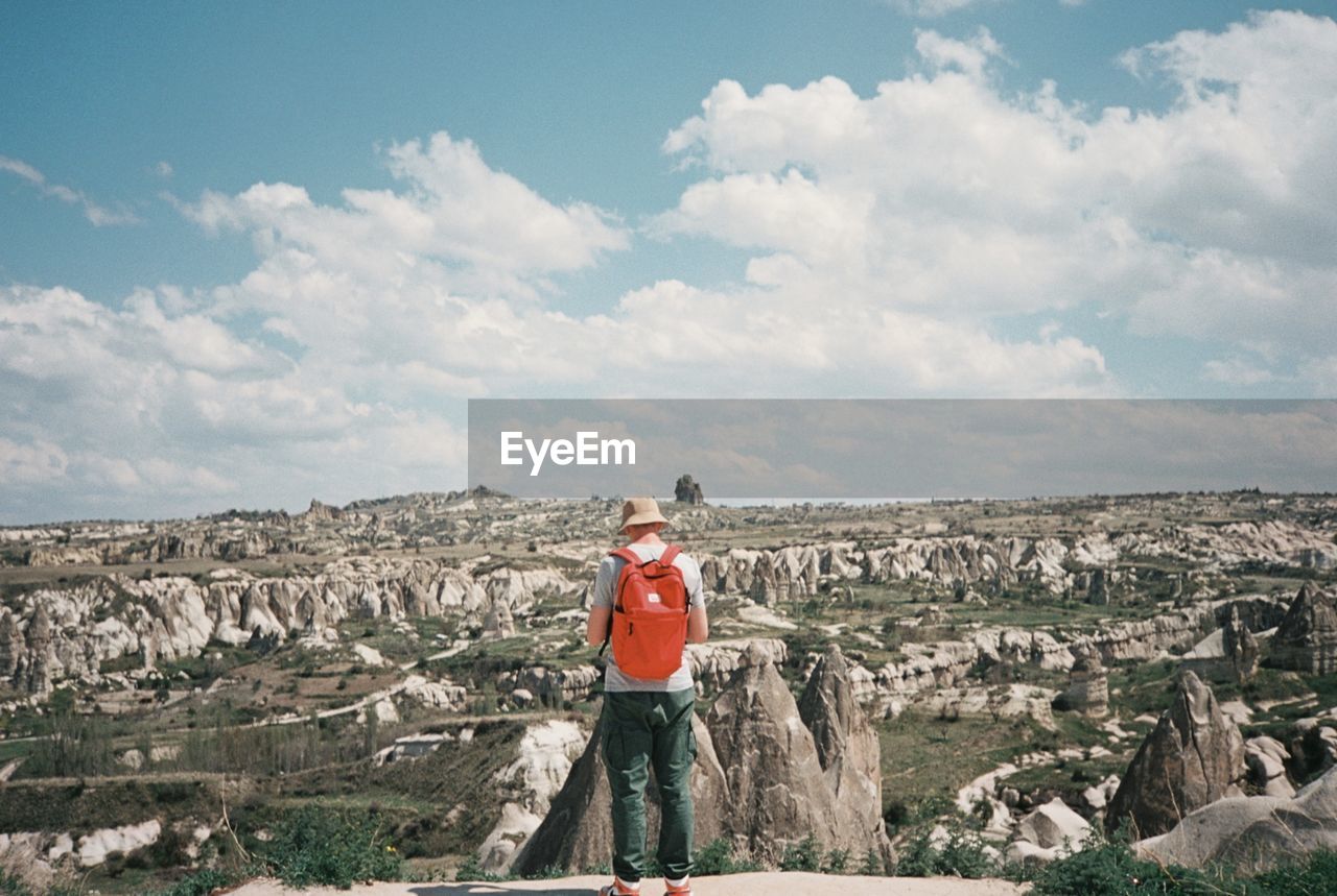 Rear view of man standing on rock against sky